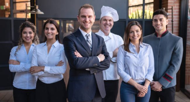Cheerful latin american team of hotel staff all facing camera smiling  - Business concepts